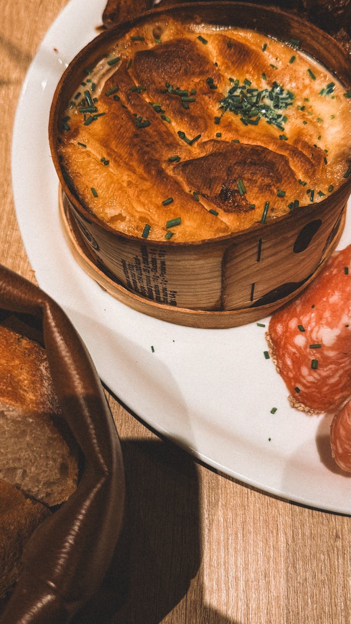 services-img Delicious baked cheese with sliced salami and fresh bread on a wooden table.